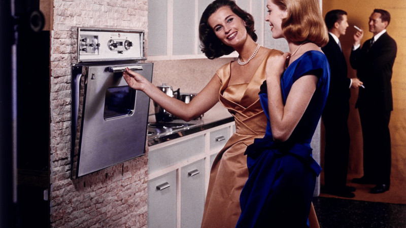 Two women smiling while observing a stove