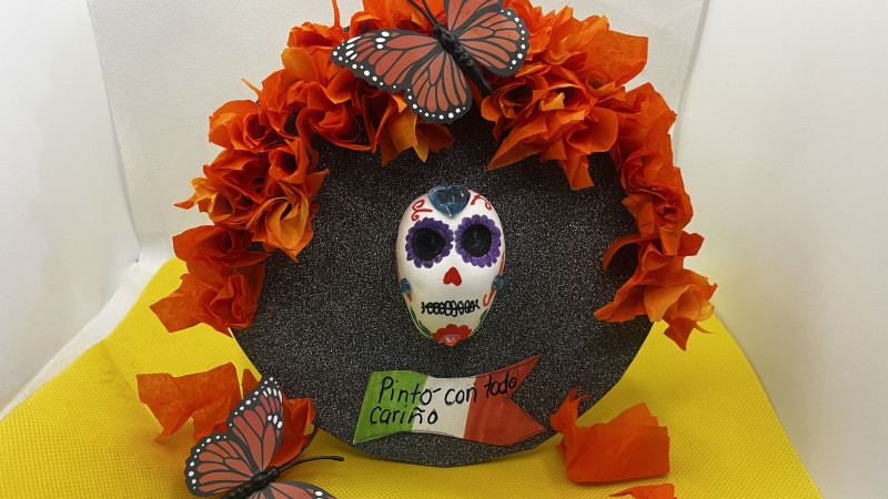 A day of the dead skull  sculpted out of model magic, on a black circle background.