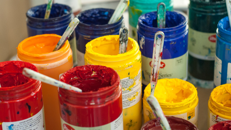 assortment of open paint jars with palette knives