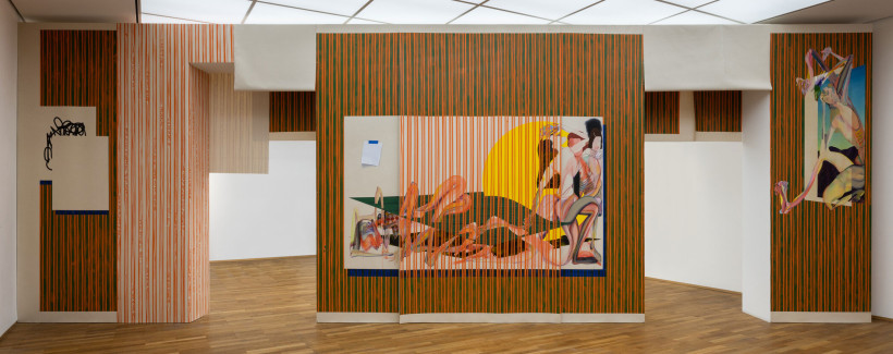 Gallery installation with colorful vertical striped walls in orange, green, and pink tones displaying contemporary figurative paintings and sculptural elements, with white geometric partitions creating distinct viewing spaces.
